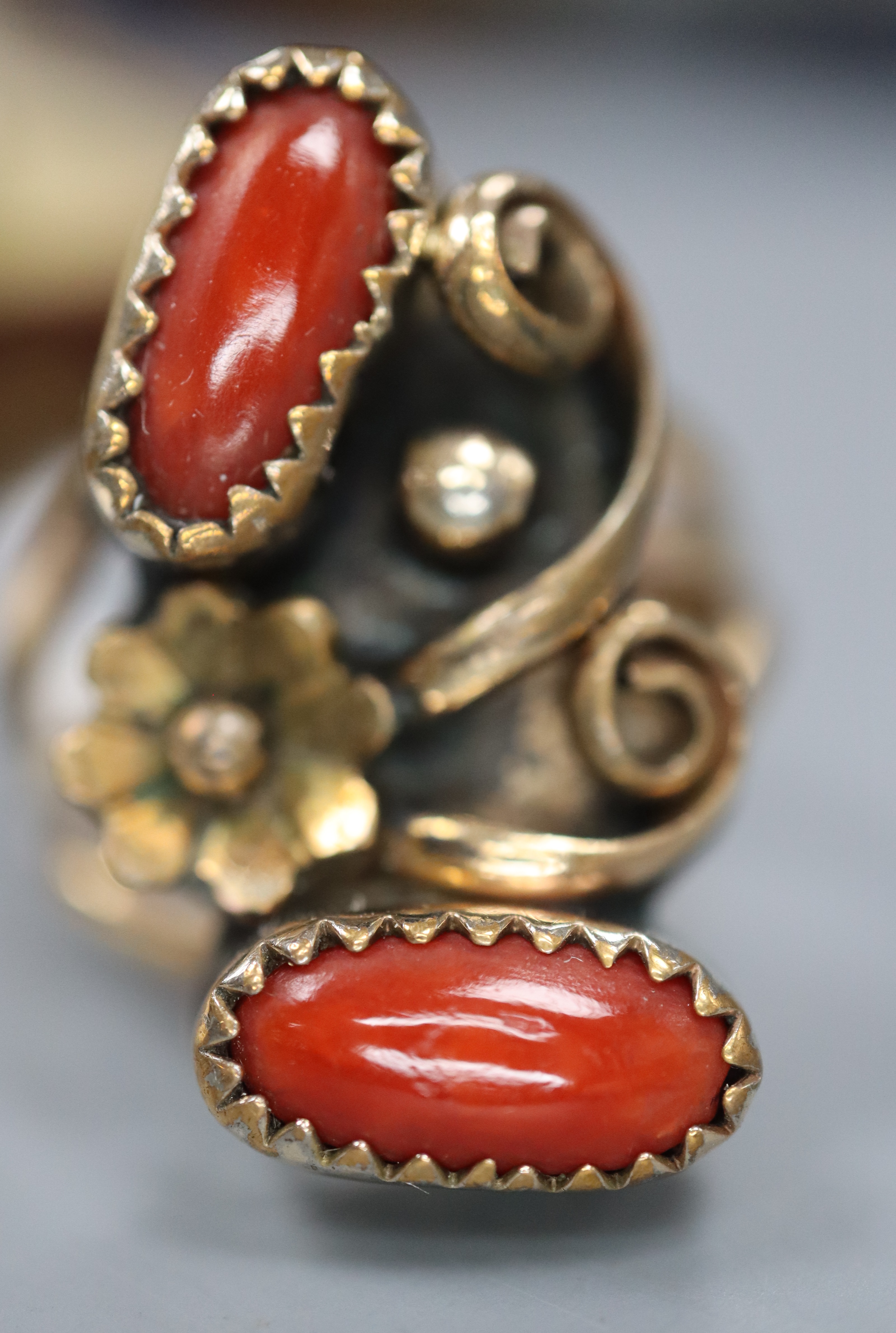 An early 20th century Arts & Crafts yellow and white metal and two stone cabochon coral set triple shank dress ring, size O,